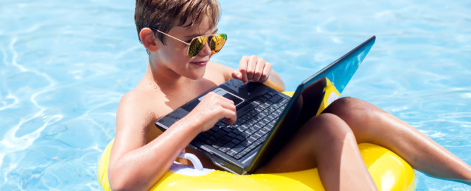 Boy Using a Laptop in the Pool