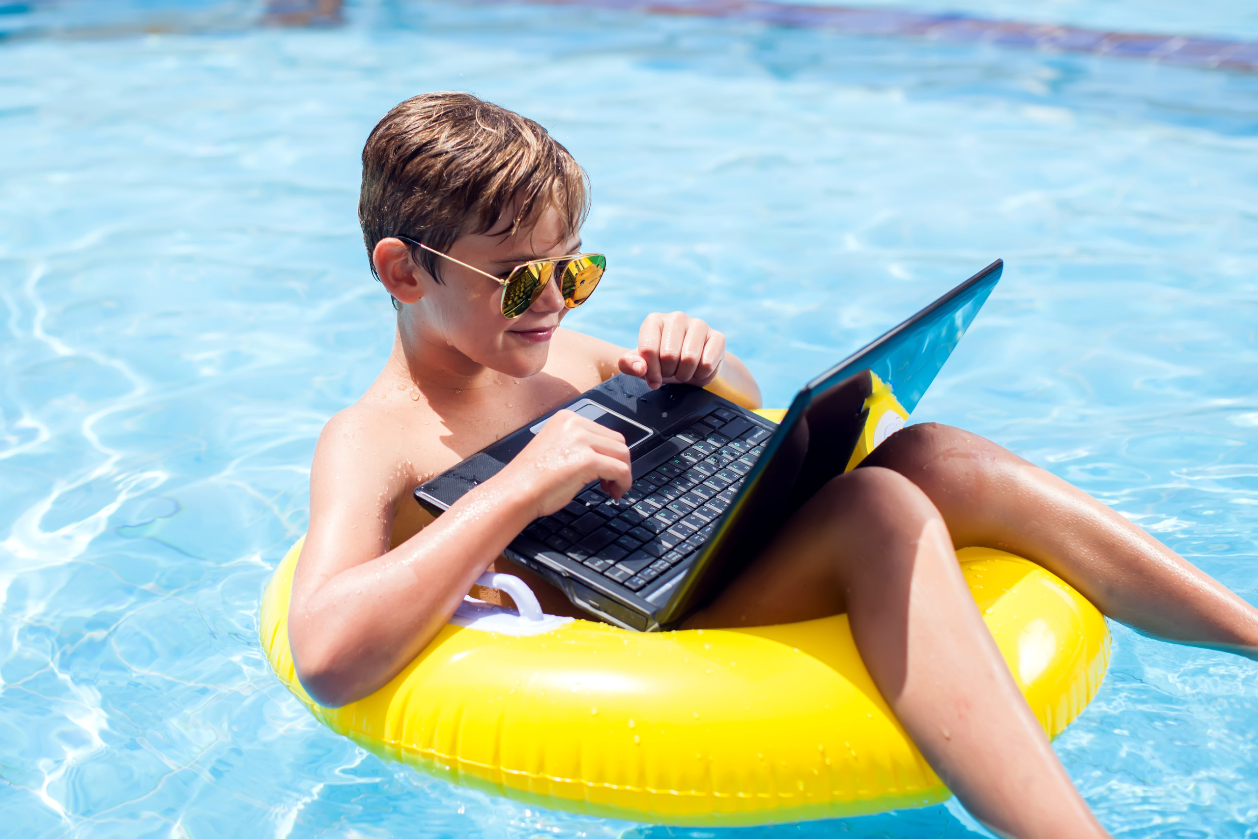 Boy Using a Laptop in the Pool